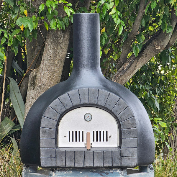 Black outdoor pizza oven with a tree in the background