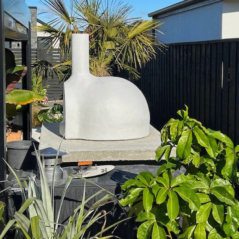 White outdoor pizza oven in a garden