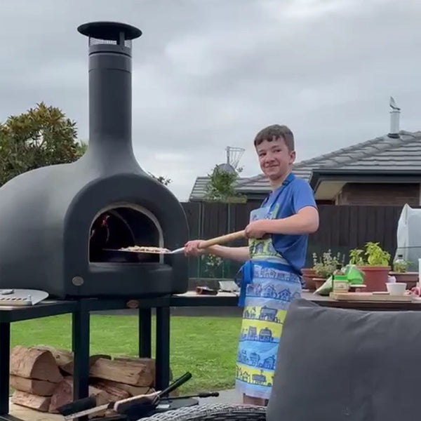 Person cooking outdoors using a portable pizza oven