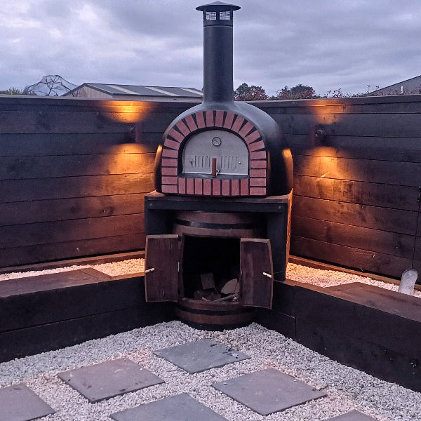 Wood-fired oven on a wooden deck with warm lighting